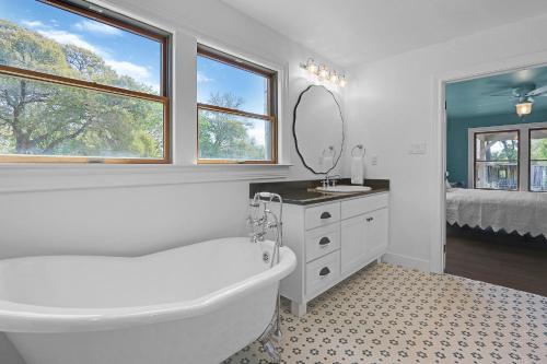 a bathroom with a tub and a sink and a mirror at Milk Bath Springs House in Dripping Springs
