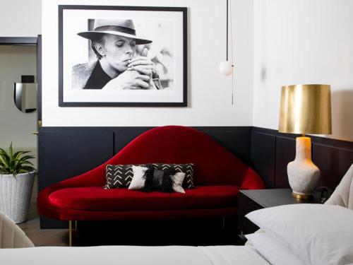 a red couch in a bedroom with a black and white picture at Virgin Hotels Dallas in Dallas
