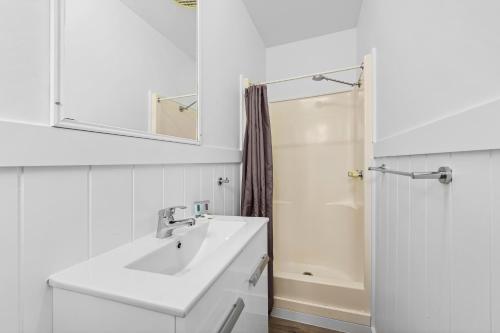 a white bathroom with a sink and a shower at Diamond Waters Caravan Park in Dunbogan