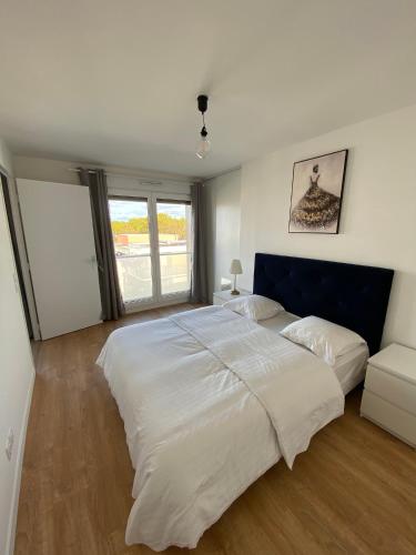 a bedroom with a large white bed and a window at Luxury appartement 5 Asnières Paris in Asnières-sur-Seine