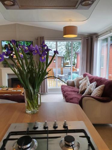 a living room with purple flowers in a vase on a table at Jaw-Dropping Lodge with Hot Tub on Lake Windermere in Windermere