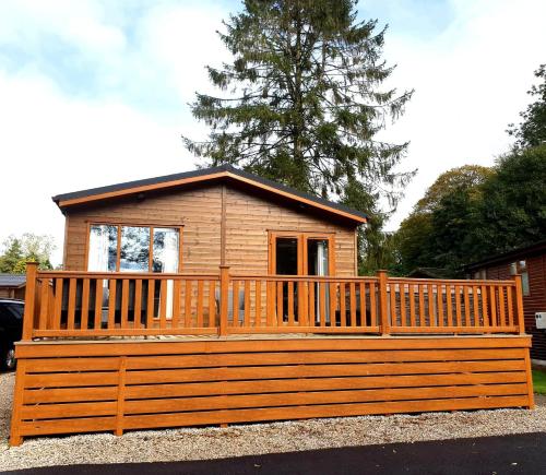 a small cabin with a large wooden deck at Jaw-Dropping Lodge with Hot Tub on Lake Windermere in Windermere