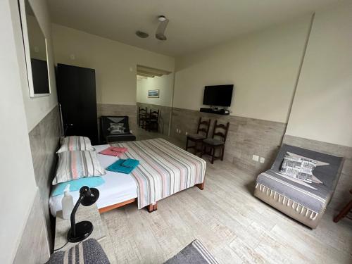 1 dormitorio con 1 cama, 1 silla y TV en Alex Rio Flats Studio Arpoador, en Río de Janeiro