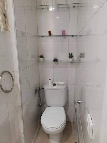 a white bathroom with a toilet and shelves on the wall at Appartement au Coeur de Casablanca in Casablanca