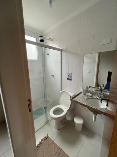 een badkamer met toilet, wastafel en douche bij Apt 2 suites com ar condicionado e piscina Ubatuba in Ubatuba