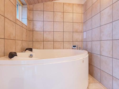 6 person holiday home in Bogense في بوجنسي: حوض استحمام أبيض في حمام به جدران من البلاط