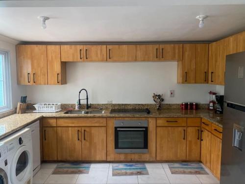 a kitchen with wooden cabinets and a sink and a dishwasher at Townhouse by The Bay, Little Bay Country Club ,Negril in Orange Bay