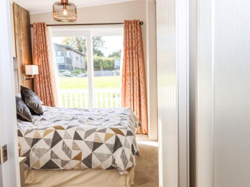 1 dormitorio con cama y ventana en Chestnut Lodge en Newton Abbot
