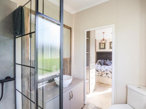 un baño con una puerta de cristal que conduce a un dormitorio en Chestnut Lodge en Newton Abbot