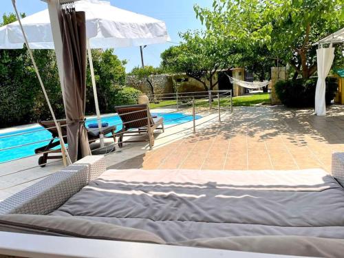 1 cama y 2 sillas junto a la piscina en Villa Melina with pool by the sea, en Palaia Epidavros