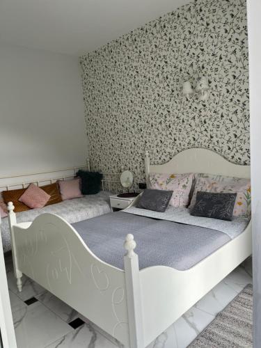 two beds in a bedroom with floral wallpaper at Dobra1 in Ściegny