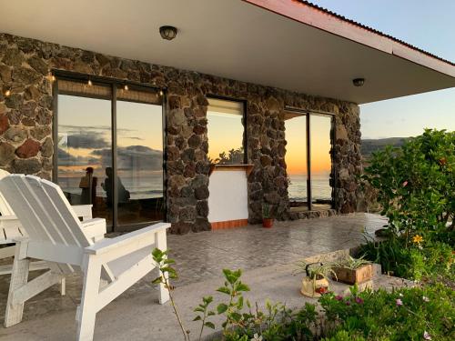 a stone house with a white chair on a patio at Cabañas & Hostal Tojika in Hanga Roa
