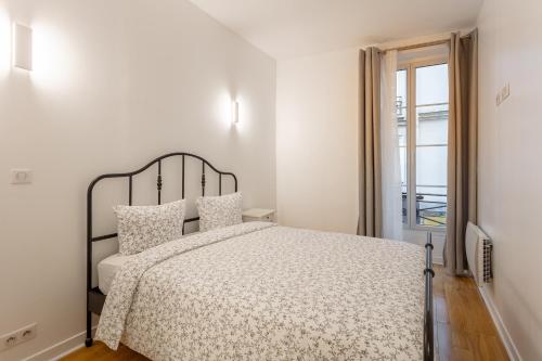a white bedroom with a bed and a window at La Suite à Chatelet in Paris