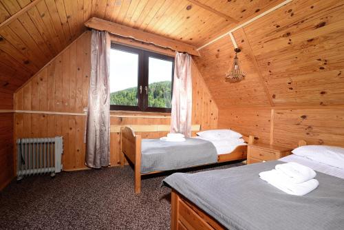 a bedroom with two beds in a wooden cabin at Perełka Bieszczady Domki in Cisna