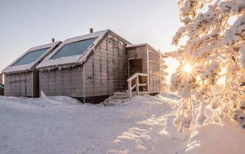un edificio cubierto de nieve con el sol en el fondo en Aurora Collection en Saariselka