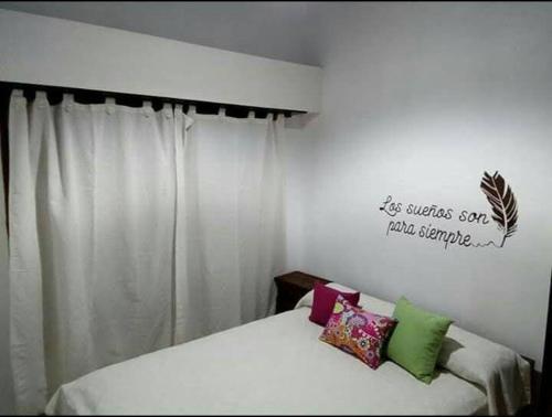Un dormitorio con una cama blanca con almohadas. en Departamento Estrada en Tandil