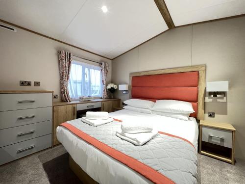 a bedroom with a large bed with a red headboard at Stewarts Resort Lodge 23 in St Andrews