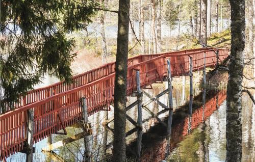 a red bridge over a river in a forest at Cozy Home In Bottnaryd With Lake View in Bottnaryd
