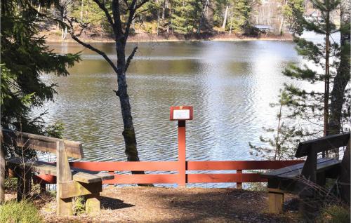a lake with two benches and a red fence at Cozy Home In Bottnaryd With Lake View in Bottnaryd