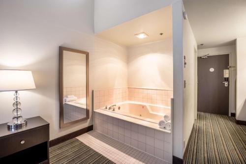 a bathroom with a tub and a large mirror at Best Western Alderwood in Lynnwood