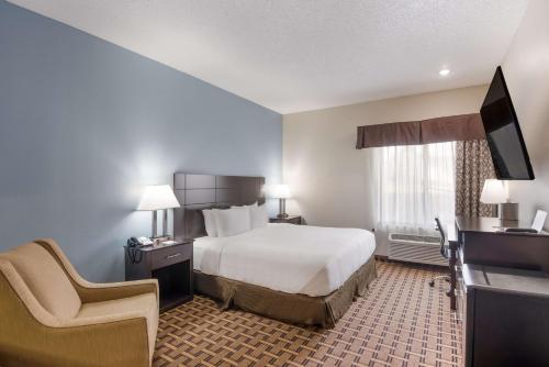 a hotel room with a bed and a chair at SureStay Plus Hotel by Best Western Coralville Iowa City in Coralville