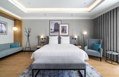 a bedroom with a large bed and two blue chairs at Radisson Hotel Riyadh Airport in Riyadh