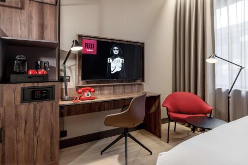 a hotel room with a desk with a tv and a red chair at Radisson RED Oslo Økern in Oslo