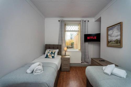 a bedroom with two beds and a tv on the wall at Cheerful 5 bed Property in Llanelli in Llanelli
