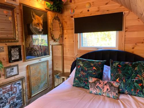 1 dormitorio con 1 cama con cuadros en la pared en Fox’s Furrow Quirky Glamping Pod with Private Hot Tub 
