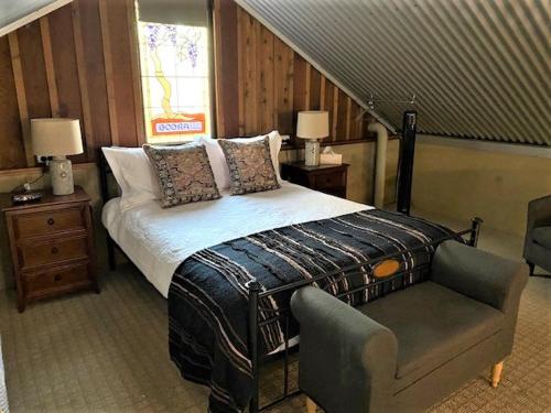 ein Schlafzimmer mit einem Bett, einem Stuhl und einer Treppe in der Unterkunft Outback Cellar & Country Cottage in Dubbo