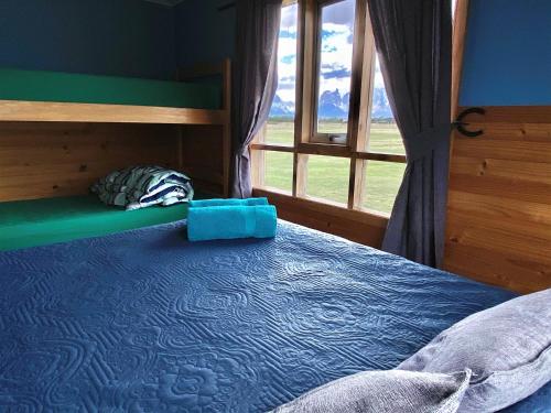 a bedroom with a bed and a large window at Vista al Paine - Refugio de Aventura in Torres del Paine