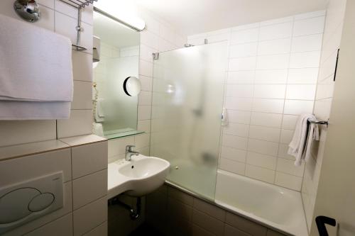 a white bathroom with a sink and a shower at Atelier Hotel Essen-City in Essen