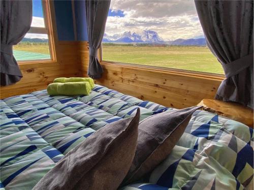 1 dormitorio con cama y ventana grande en Vista al Paine - Refugio de Aventura, en Torres del Paine