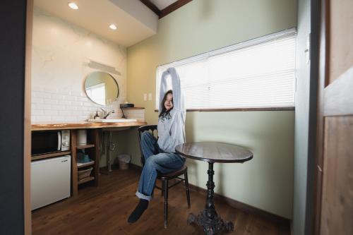 a woman sitting in a chair in a room with a table at Traditional Apartment Takamatsu Guesthouse in Takamatsu