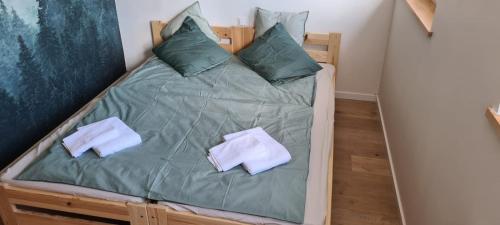 a bed with green sheets and pillows in a room at Apartament Tymon in Karpacz