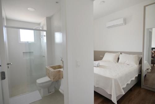 a white bathroom with a bed and a shower at Vila do Centro Apart Hotel in Bombinhas
