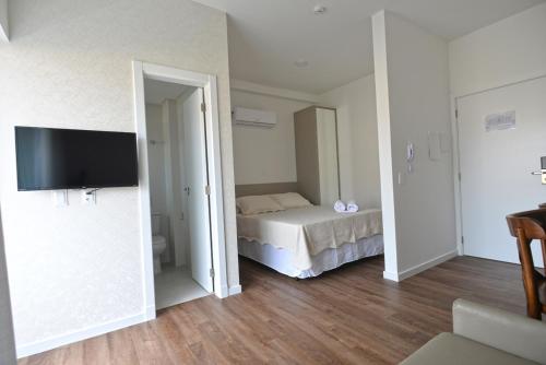 a bedroom with a bed and a television in it at Vila do Centro Apart Hotel in Bombinhas