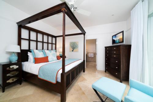 a bedroom with a canopy bed and a blue chair at The Regent Grand in Grace Bay