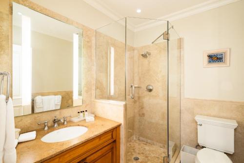 a bathroom with a sink and a glass shower at The Regent Grand in Grace Bay