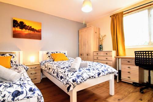 ein Schlafzimmer mit zwei Betten und einem Schreibtisch und einem Fenster in der Unterkunft The Chinatown Home - Private Garden, NETFLIX, BBQ & Bar in Birmingham