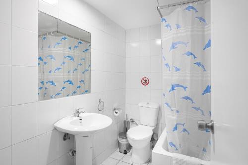 uma casa de banho com um lavatório, um WC e uma cortina de chuveiro. em Diros Hotel em Atenas