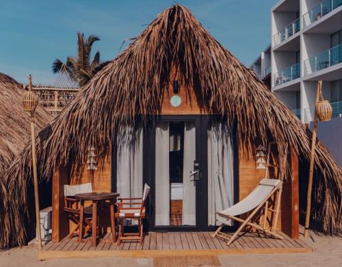 a hut with a table and chairs on a beach at qema Mancora in Máncora