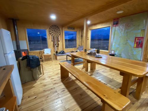 comedor con mesa de madera y banco en Vista al Paine - Refugio de Aventura, en Torres del Paine