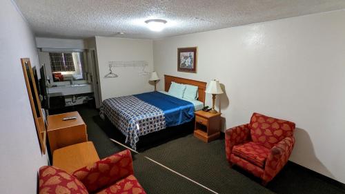 a hotel room with a bed and two chairs at Eufaula Inn in Eufaula