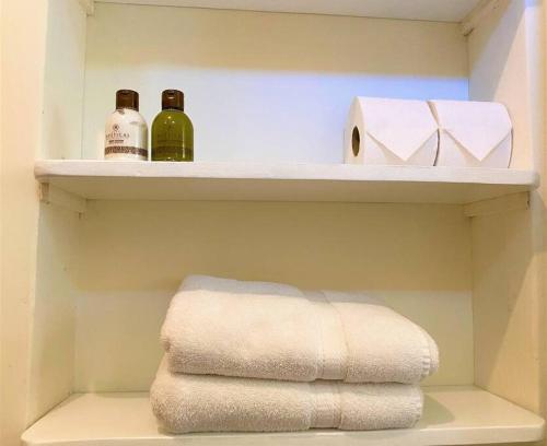a bathroom with two bottles and towels on shelves at Adorable Private Studio in Tijuana