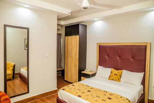 1 dormitorio con 1 cama grande y espejo en Hotel 61, en Ikeja