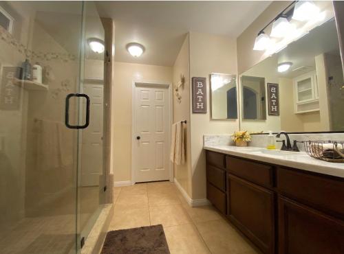 ein Bad mit einer Dusche, einem Waschbecken und einem Spiegel in der Unterkunft Ranch House in Bakersfield