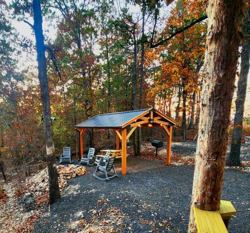 a gazebo with a picnic table and chairs in the woods at The Windstorm Cabin - Pet-friendly & a 2-person Jacuzzi hot tub! in Marshall