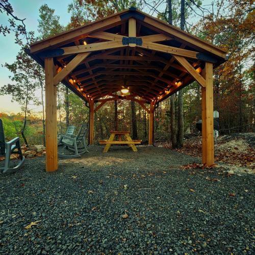 a wooden pavilion with a picnic table in the woods at The Windstorm Cabin - Pet-friendly & a 2-person Jacuzzi hot tub! in Marshall