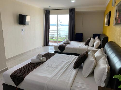 a hotel room with two beds and a window at Lumuda Hotel in Lumut